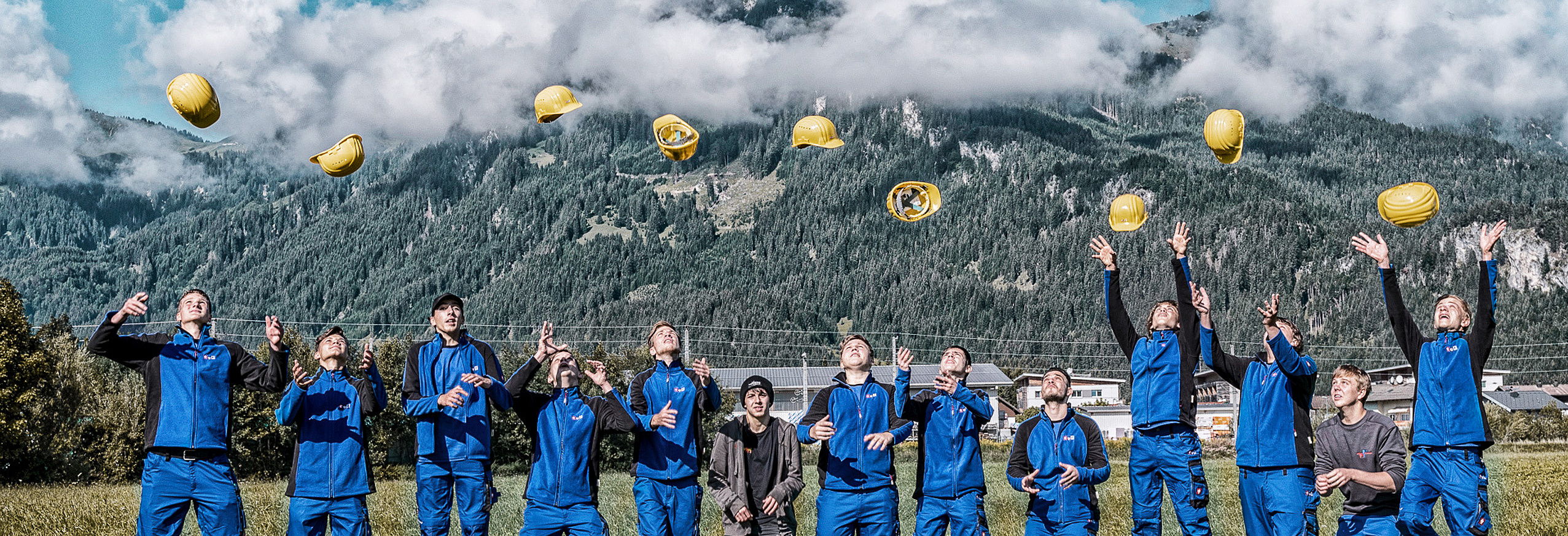 Gruppenbild Lehrlinge werfen im Freien ihre Helme in die Luft