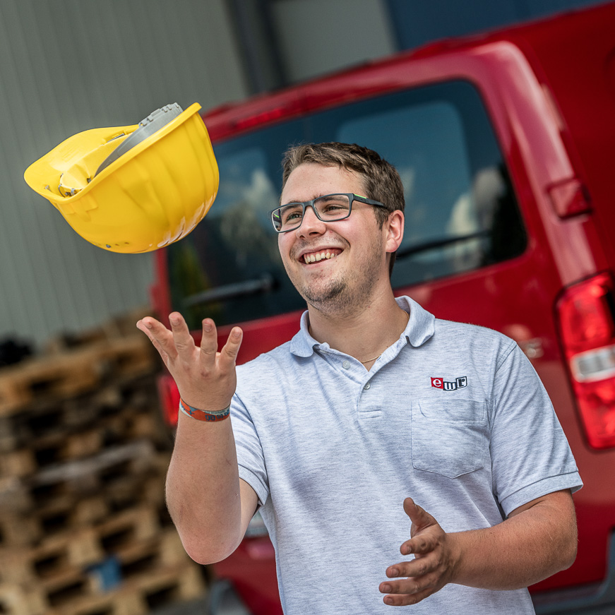 Arbeiter wirft fröhlich seinen Helm in die Luft