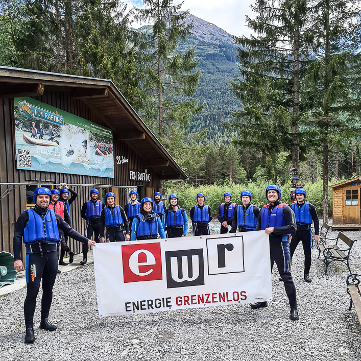 Gruppe mit Raftinganzügen und Logo-Banner EWR